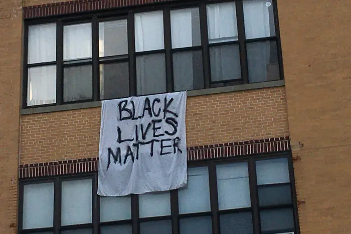 A banner hanging from the roof of a Flushing Avenue apartment
